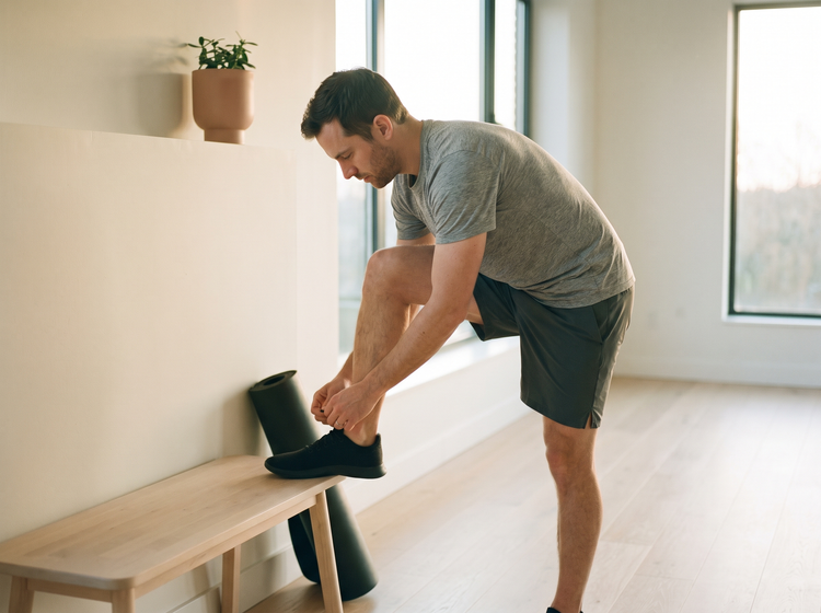 Man lacing a trainer in a bright home gym before training